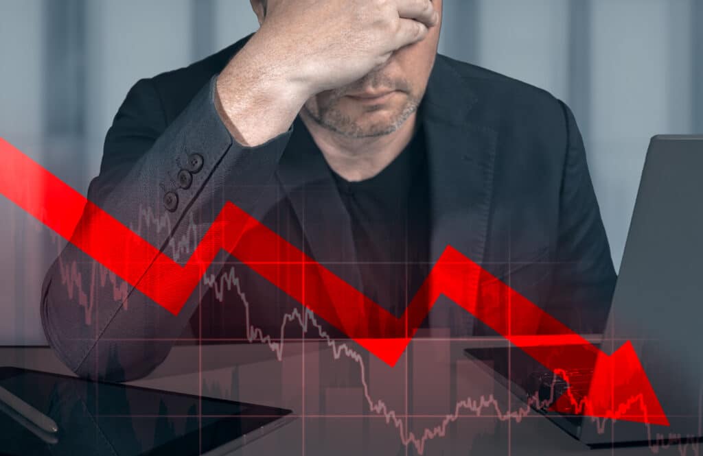 businessman holding hands on head looking at graph of declining profit. Businessman Looking Up At Chart That Indicates Falling Dollar. Graphs representing stock market crash caused ทำไมเมื่อธนาคารกลางขึ้นดอกเบี้ย หุ้นจึงร่วง ?
